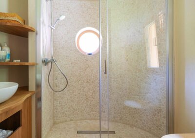Huberto modular house, © Carina Rebler Modern shower with round glass wall and small porthole.