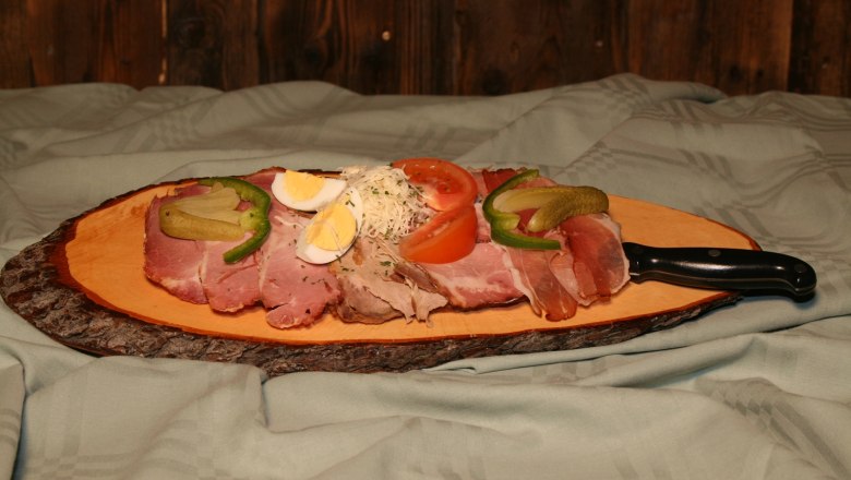 Jause Familie Kamper, © Familie Kamper Eine rustikale Jause mit Aufschnitt, Ei, Tomate und Gurke auf einem Holzbrett.