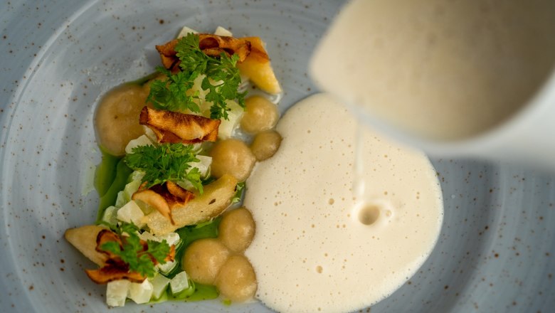 Fine cuisine at the Sporthotel, © Sporthotel Semmering Gourmet dish with foam and vegetables on a plate.