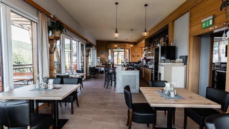 Kulinaria, © MAXSAM GmbH_perfect print Innenansicht eines modernen Cafés mit Holzmöbeln und großen Fenstern.