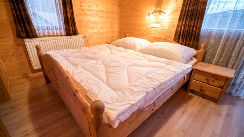 Wohnung "Panorama" Schlafzimmer, © Familie Morgenbesser Gemütliches Schlafzimmer mit Holzwänden, Doppelbett und Nachttisch in einer Ferienwohnung.
