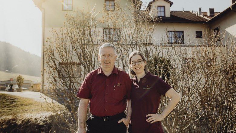 In service: Katharina Schwarz & Peter Pichler, © Niederösterreich Werbung/Sophie Menegaldo Two people in red shirts stand smiling in front of a building.