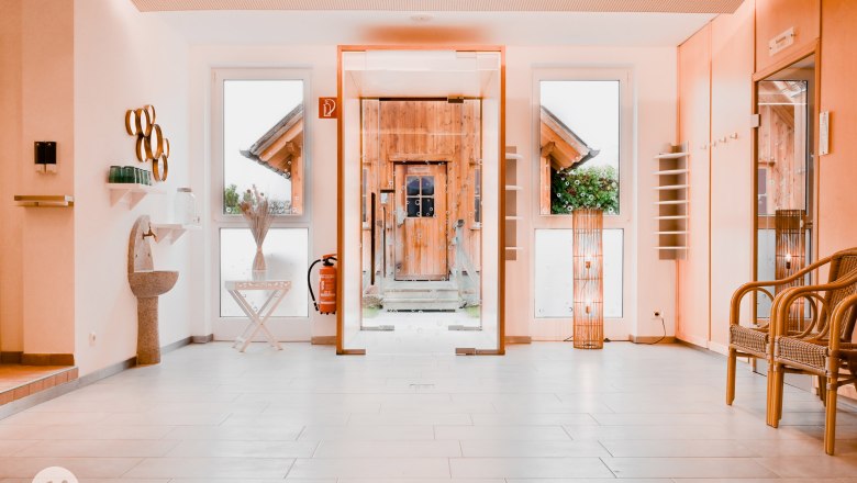 Aufenthaltsbereich, © TheVerve-Agentur (theverve.at) Moderner Aufenthaltsbereich mit Glaswand, Holztür, Dekorationen und Sitzgelegenheiten.