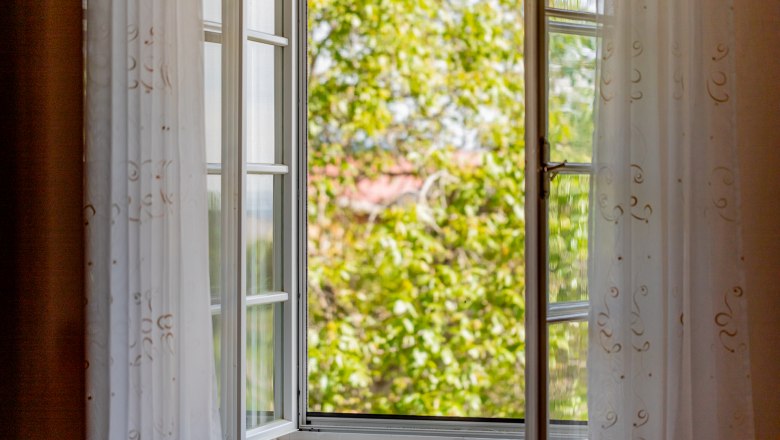 Woltron Manor, © Wiener Alpen / Christian Kremsl Open window with white curtains, view of green trees.