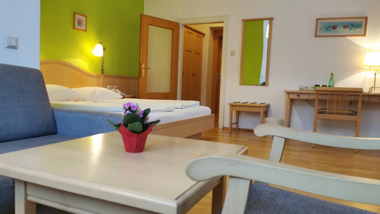 Zimmer im Hotel Belvedere, © Hotel Belvedere Hotelzimmer mit grünem Akzent, Bett, Schreibtisch und Sessel.