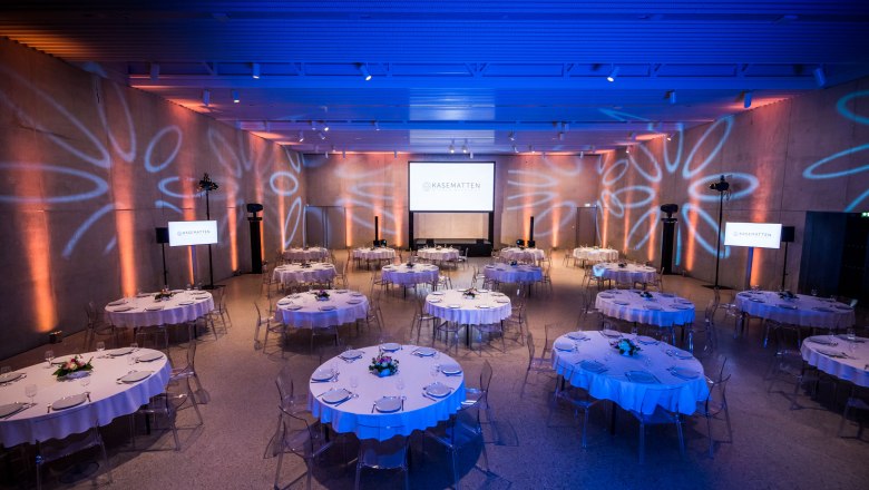 New Bastei gala seating, © Kasematten Wiener Neustadt Elegant event room with round tables and blue lighting.