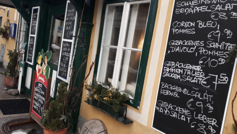 Stiegenwirtshaus Gloggnitz, © Stiegenwirtshaus/Stummer Eingang eines Wirtshauses mit mehreren Tafeln, die Speisen und Preise anzeigen.