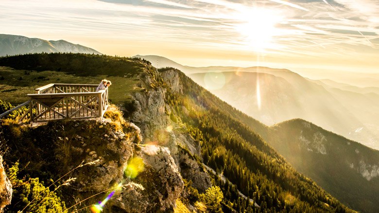 Ottohaus lookout, © Niederösterreich-Werbung/ Robert Herbst Viewing platform on a mountain with a view of wooded hills and sunset.