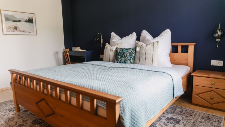 Schlafzimmer Feriennest Zehetbauer, © heiter-weiter.at/Karl Stangl Gemütliches Schlafzimmer mit Holzbett, blauer Wand und dekorativen Kissen.