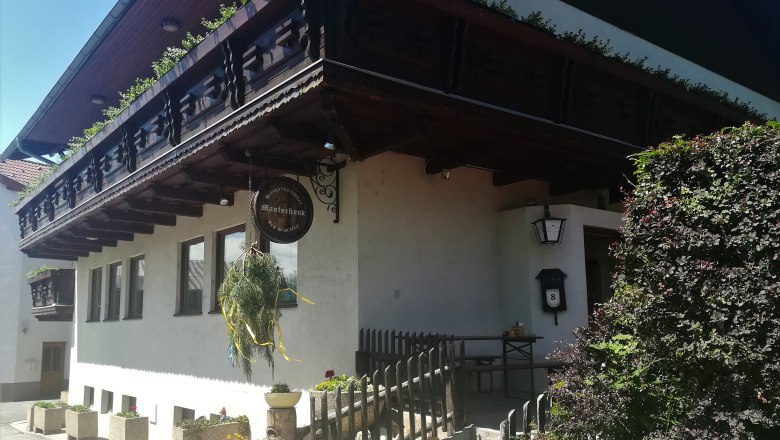 Weingartleitenhof, © Wiener Alpen Traditionelles Gebäude mit Holzbalkon und Schild mit der Aufschrift "Mostschank".