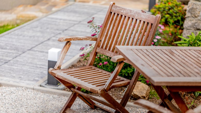 Ferienwohnung Semler, © Wiener Alpen / Christian Kremsl Holzstuhl und Tisch im Garten mit Blumen im Hintergrund.
