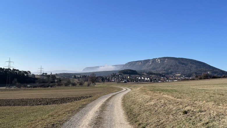Blickplatz Rotes Kreuz, © Wiener Alpen/Katharina Lechner Landschaft mit Feldweg, Bergen und blauem Himmel.