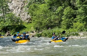 Tubing Wildnis Zentrum Nasswald, © Georg Bergthaler Personen beim Tubing auf einem Fluss in einer grünen, bewaldeten Umgebung.