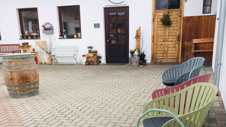 Sitzmöglichkeit vorm Kaufhaus, © Das kaufhaus, Peter Wochesländer Sitzbereich vor einem Kaufhaus mit bunten Stühlen und einem Fass.