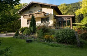 Ferienhaus Schlager, © Claudia Schlager Ein zweistöckiges Ferienhaus mit Balkon und Garten, umgeben von Bäumen und Wiese.