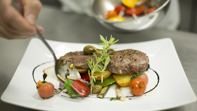 Genuss neu definiert., © Patrick Haberler Ein Teller mit kunstvoll angerichtetem Fleisch, Gemüse und Kräutern.