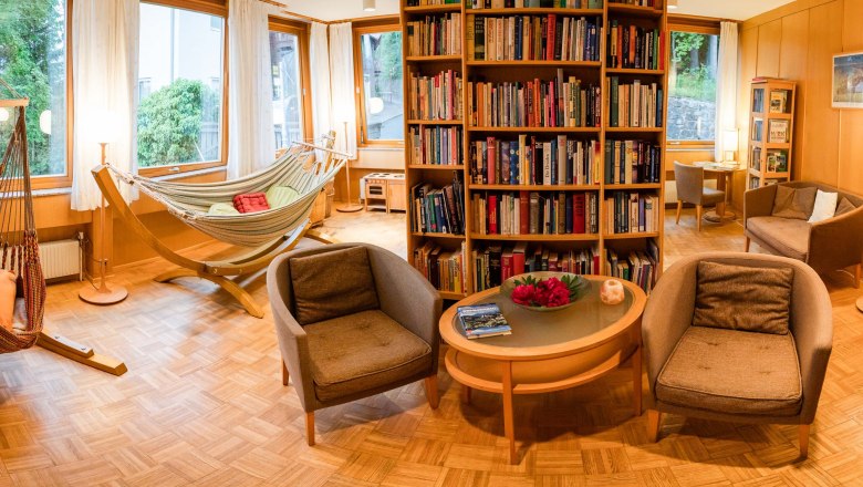 Bibliothek - Panoramahotel Wagner, © Sebastian Freiler Gemütliche Bibliothek mit Hängematten, Sesseln und Bücherregalen in einem Hotel.