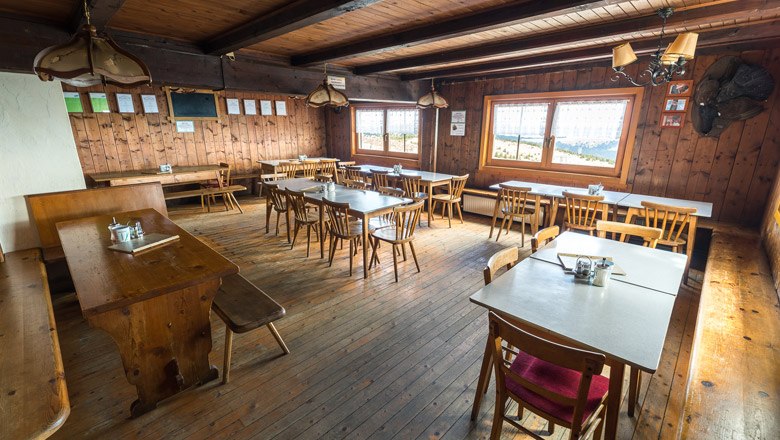 The cozy parlor invites you to take a break, © Wiener Alpen, Christian Kremsl Cozy wooden hut with tables and chairs, rustic furnishings.