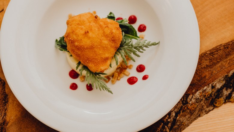 Baked egg on potato and beet puree, © Niederösterreich Werbung/Klaus Engelmayer A baked egg on a plate with puree and red polka dots.