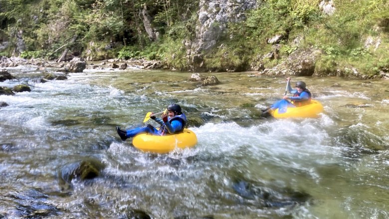 Tubing Wildnis Zentrum Nasswald, © Georg Bergthaler Zwei Personen beim Tubing auf einem Fluss in einer bewaldeten Umgebung.