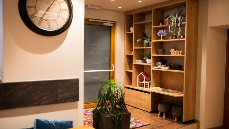 Room at Koll Bistro Kirchschlag, © Koll GmbH Interior view of a bistro with large decorative clock, shelf and children's play corner.