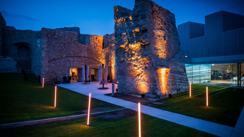 The chert, © Christian Husar Illuminated ruins with modern buildings in the background at dusk.