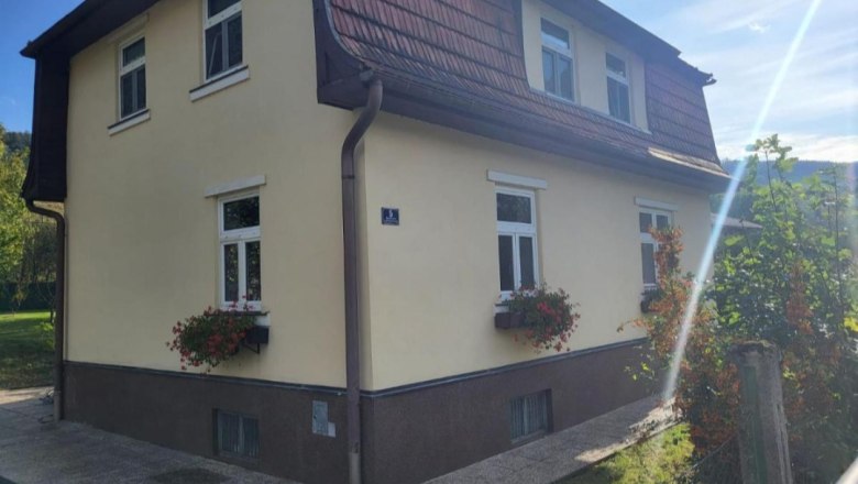 Leo-Hof Ferienwohnung Eva, © Leo-Hof/Sandra Reinisch Zweistöckiges gelbes Haus mit roten Dachziegeln und Blumenkästen an den Fenstern.