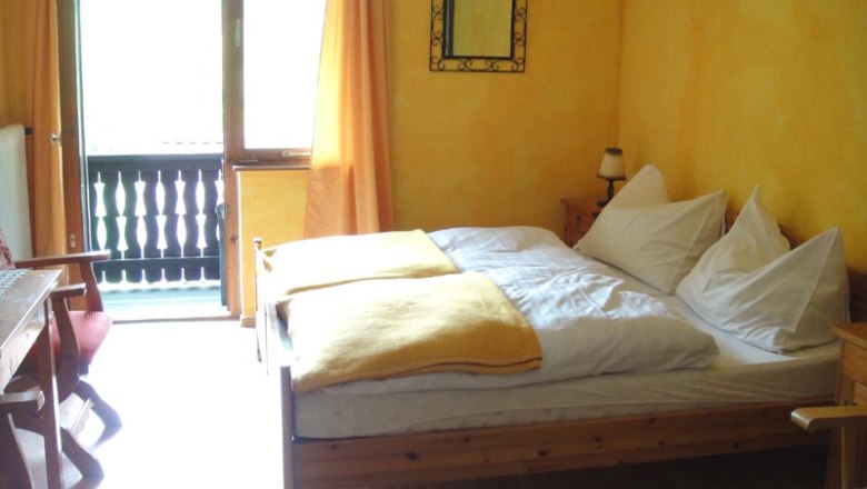 Zimmer Jägerstube, © Familie Kellner Gemütliches Zimmer mit Holzmöbeln, gelben Wänden und Balkon.