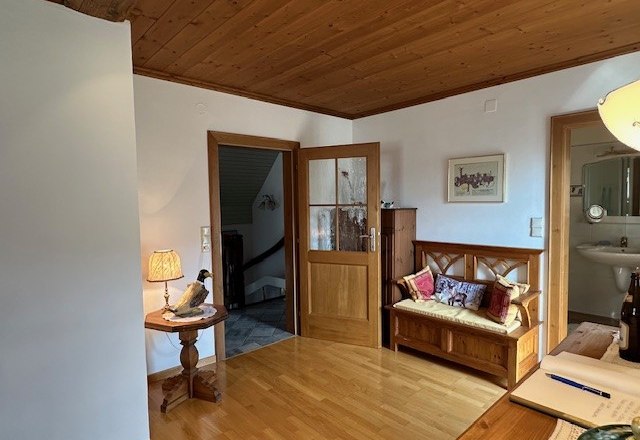 Schlafzimmer mit angrenzenden Badezimmer, © Heidi Peer Holzvertäfeltes Zimmer mit Bank, Tischlampe und offenem Zugang zu einem Badezimmer.