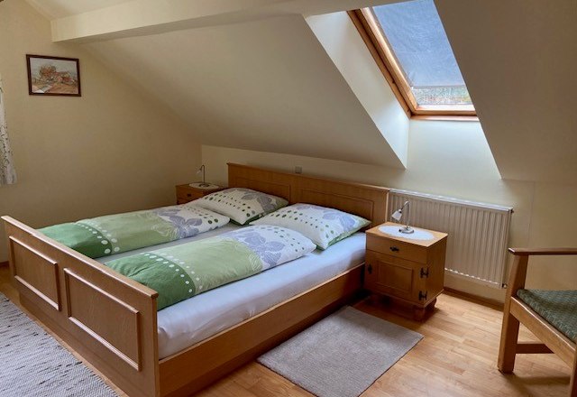 Double room Jansch, © Wiener Alpen Cozy double room with skylight, wooden bed and bedside table.
