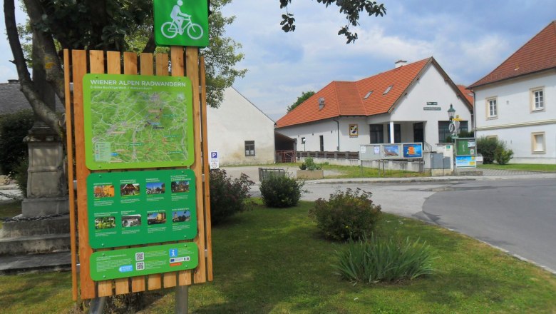Walpersbach bike start sign, © ©Wiener Alpen Cycle starting point board in Walpersbach with map and information, surrounded by buildings and trees.