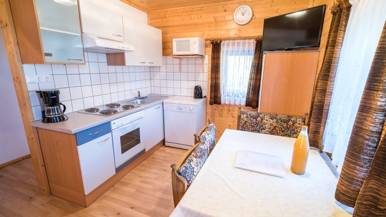 Wohnung "Panorama" Küche, © Familie Morgenbesser Gemütliche Küche mit Holzwänden, Esstisch, Herd, Kaffeemaschine und Fernseher.