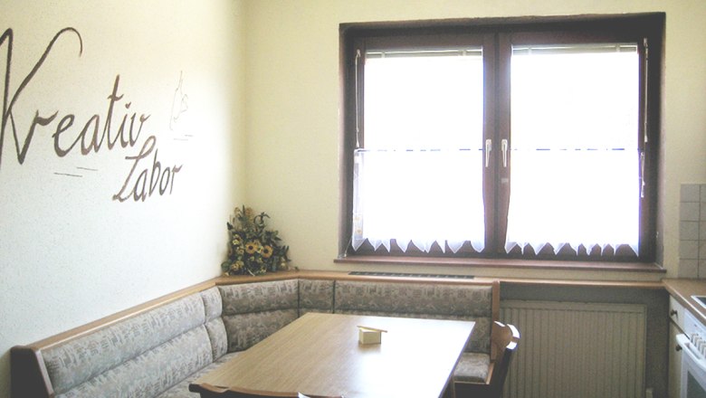 Dining table in the kitchen, © Anke Spreitzer Kitchen with corner bench, table and 'Kreativ Labor' lettering on the wall.