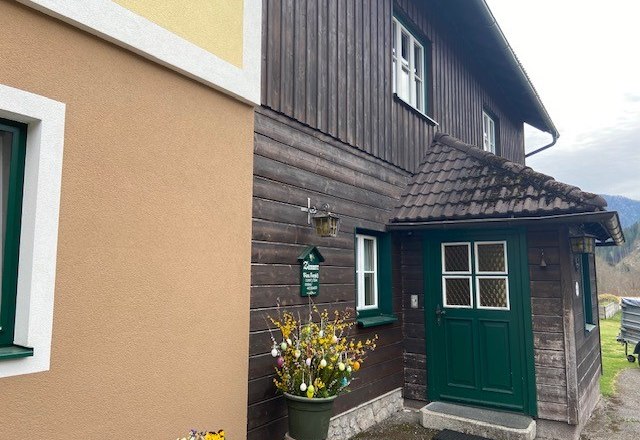 Entrance private room family Jansch, © Wiener Alpen Entrance of a traditional house with wooden paneling and green door frame.