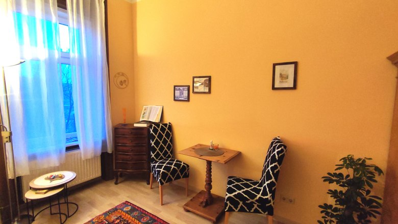 Villa Petterhof Zimmer, © Villa Petterhof Gemütliches Zimmer mit zwei Stühlen, kleinem Tisch, Teppich und Pflanzen.