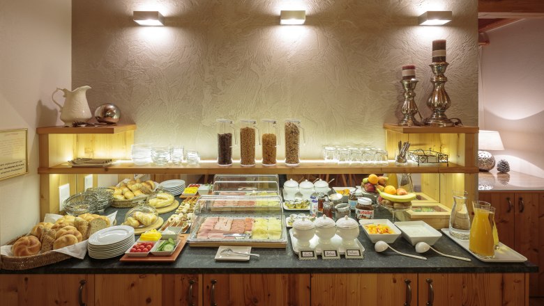 Buffet, © rosinger Ein Frühstücksbuffet mit Brötchen, Aufschnitt, Müsli, Obst und Getränken auf einem Holztresen.