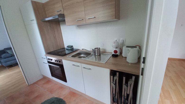 Küchenzeile, © Dekic-Ouaja Moderne Küchenzeile mit Holz- und weißen Elementen, Herd, Spüle und Küchengeräten.