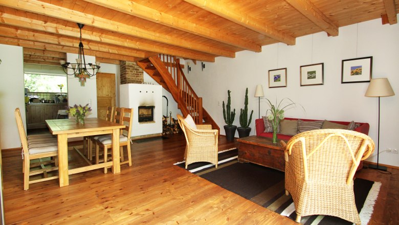 Ferienhaus Unternberg - Wohnzimmer, © Haus Gruber-List Gemütliches Wohnzimmer mit Holzboden, Esstisch, Kamin, Treppe und Pflanzen.