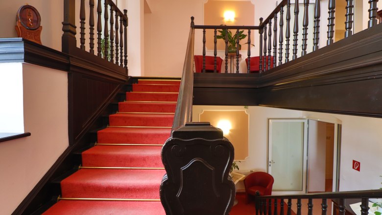 Hotel - Stiegenaufgang, © Fam. Auer GMBH Hotelstiegenaufgang mit rotem Teppich und dunklem Holzgeländer.