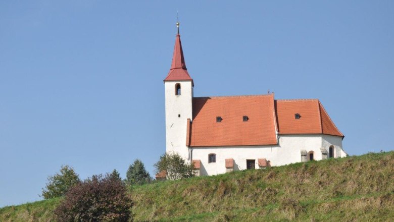 Pfarrkirche Ofenbach, © Thermengemeinden Pfarrkirche Ofenbach auf einem Hügel mit blauem Himmel im Hintergrund.