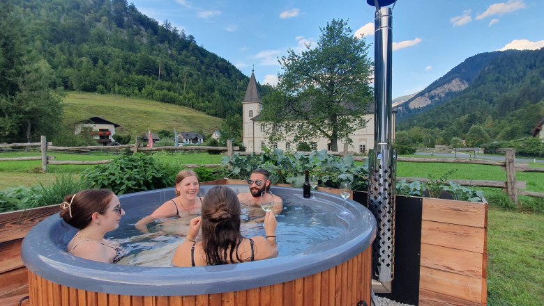 Glamping Wildnis Zentrum Nasswald, © Jonathan Clark Gruppe von Menschen in einem Hot Tub in ländlicher Umgebung.