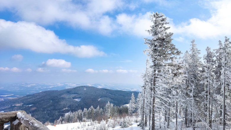 Ausblick der Stoa Alm, © 2021 Maxsam GmbH Verschneite Berglandschaft mit Bäumen und blauem Himmel.
