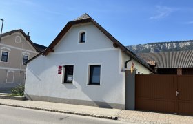 Ferienhaus Höflein, © Anton Sommer Ein kleines, weißes Ferienhaus mit braunem Tor und Bergkulisse im Hintergrund.