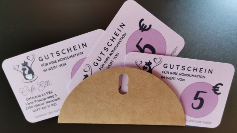 Cafe Elli, © Cafe Elli Drei rosafarbene Gutscheine im Wert von 5 Euro für das Cafe Elli, teils in einem Umschlag.