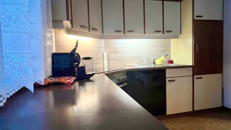 Heidis Place_Küche, © Wiener Alpen Küche mit dunkler Arbeitsplatte, hellen Schränken und Holzdecke.