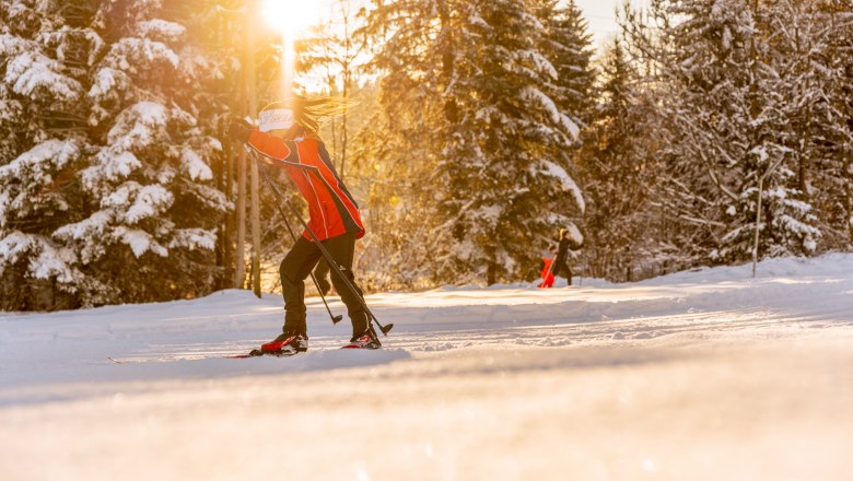 Cross-country ski trail Zöbern, © Wiener Alpen, Martin Fülöp Cross-country skiers on a snow-covered trail at sunset.