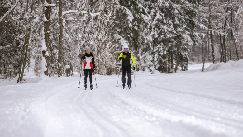 Mühlenloipe Hochneukirchen, © Wiener Alpen, Martin Fülöp Zwei Personen beim Skilanglauf auf einer verschneiten Waldloipe.