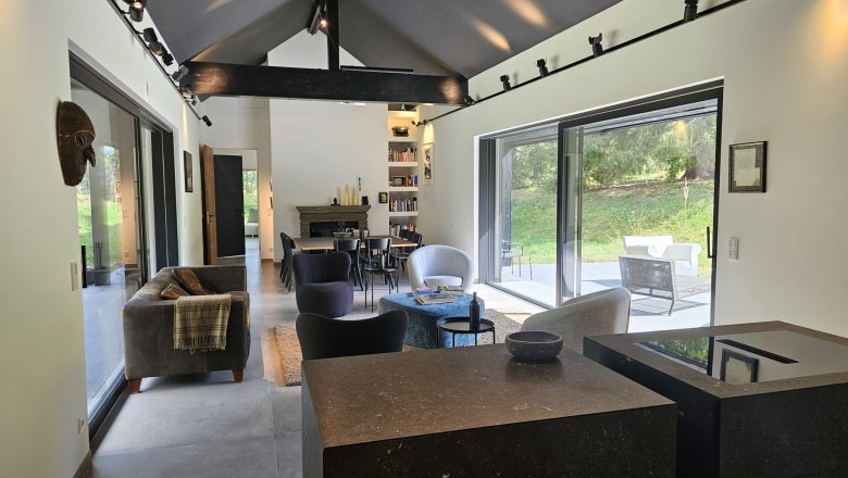 Walddenke, Aufenthaltsbereich Küche Wohnzimmer, © Mag. Plötzeneder Modernes Wohnzimmer mit großen Fenstern, Sofas und Kamin.