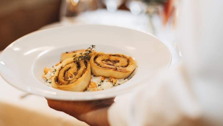 Porcini mushroom roulade, © Niederösterreich Werbung/David Schreiber A plate of porcini mushroom roulades garnished with herbs is served.