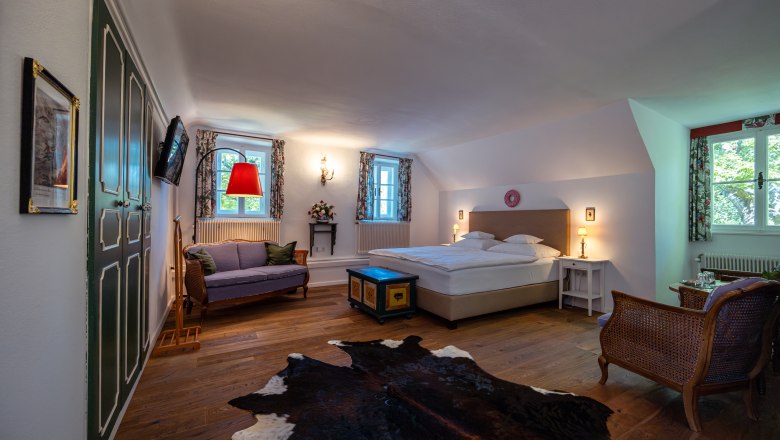 Landsitz Oberhof, © Niederösterreich Werbung / Maximilian Pawlikowsky Gemütliches Schlafzimmer mit Doppelbett, Sofa, Holzboden und Kuhfell-Teppich.